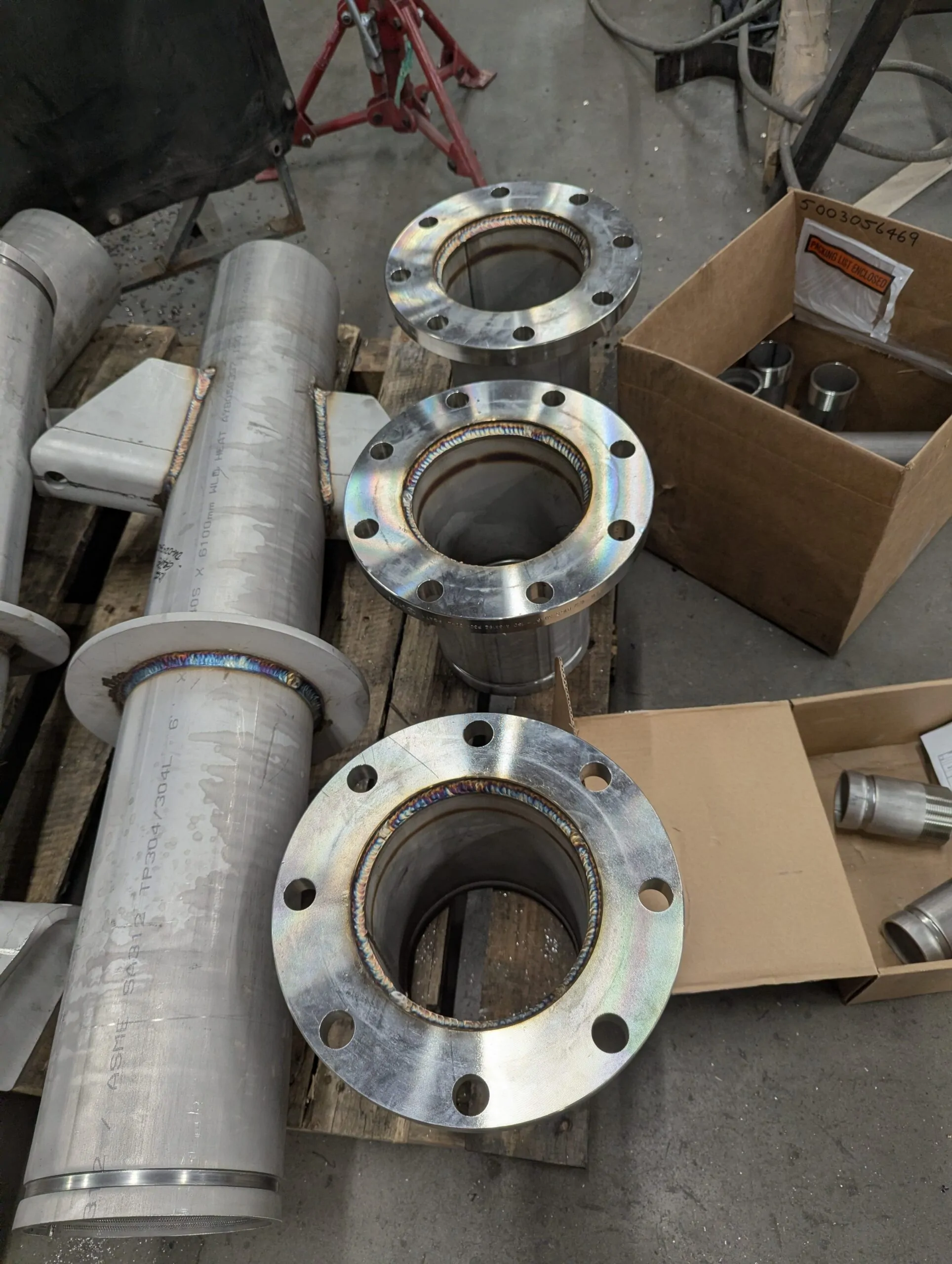 Stainless steel flange spool pieces on a workshop bench